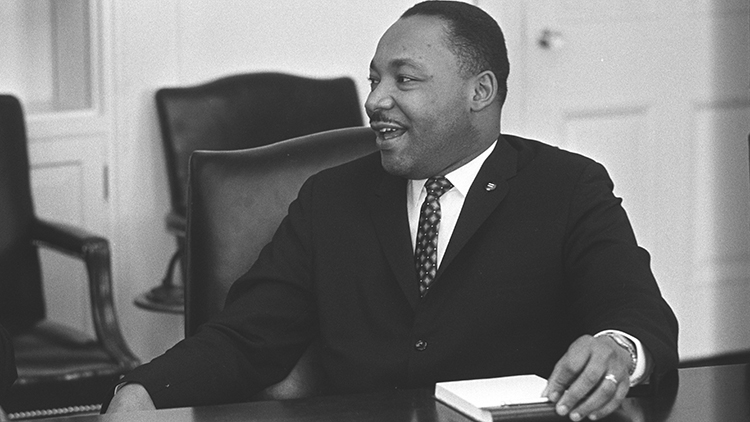 Dr. Martin Luther King, Jr. sitting at desk.