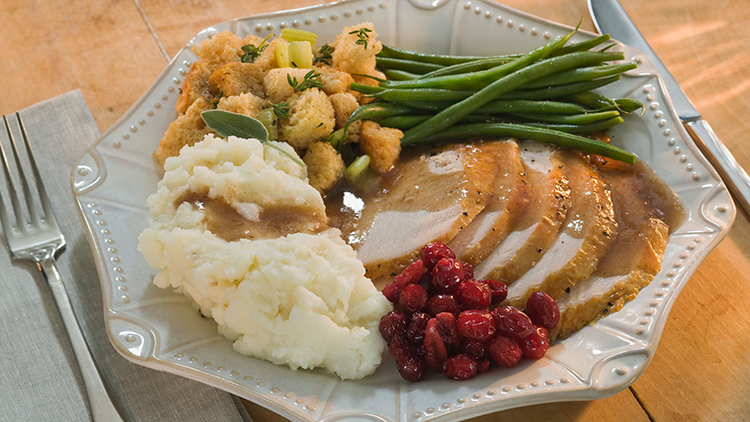 A Thanksgiving dinner with turkey, stuffing, mashed potatooes, green beans, and gravy