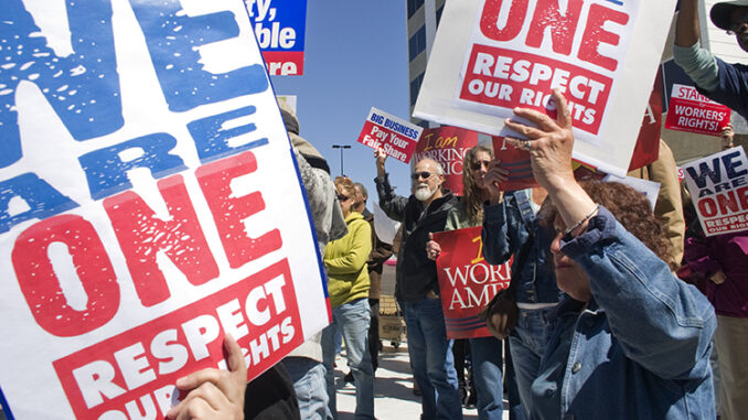 People holding posters up at a rally for workers rights and jobs in America.