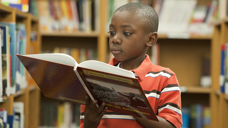 boy reading book in library