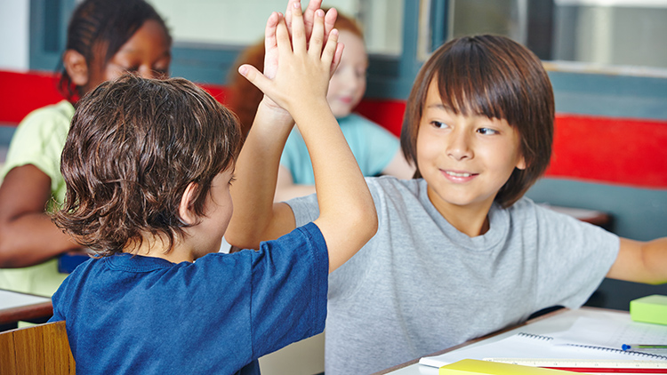 Two boys high-fiving in class