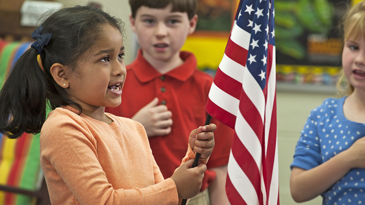 Student holding flag reciting Pledge of Allegiance