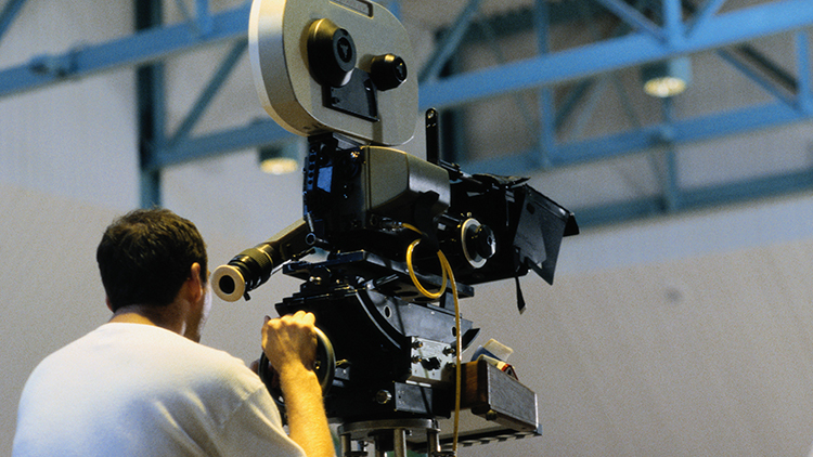 Cameraman operating movie camera, rear view