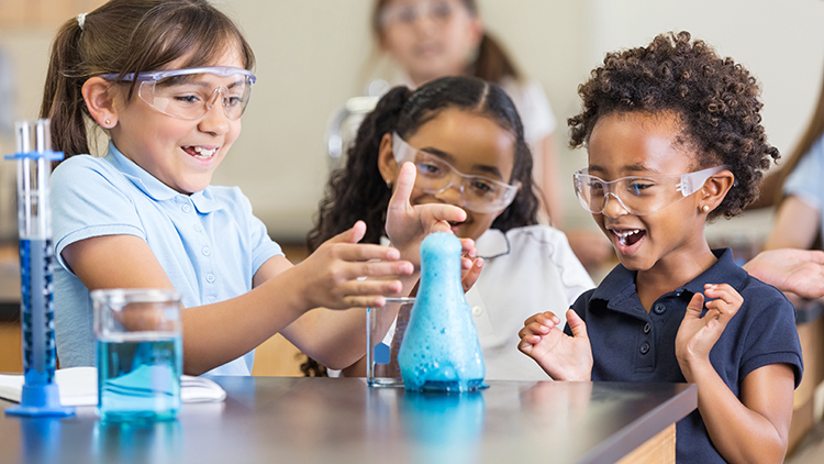 Chicas emocionadas que usan la química en el aula de ciencias elemental