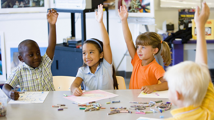 Children raising their hands to answer a question in art class
