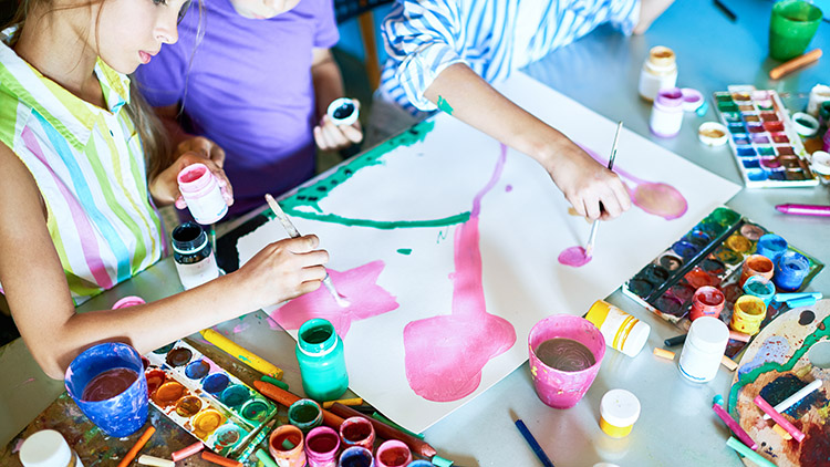 Grupo de niños irreconocibles pintando cuadros con acuarelas trabajando juntos