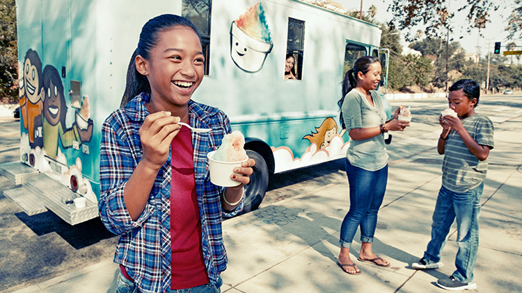 Muchacha comiendo helado de un camión